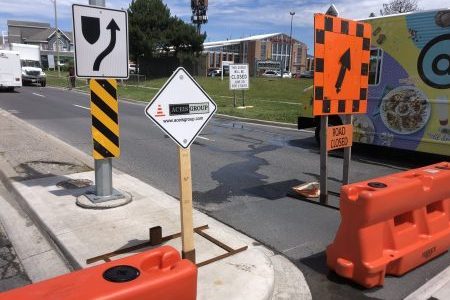 Water barriers and signage depicting Aceis Group road closure for event in the roadway.